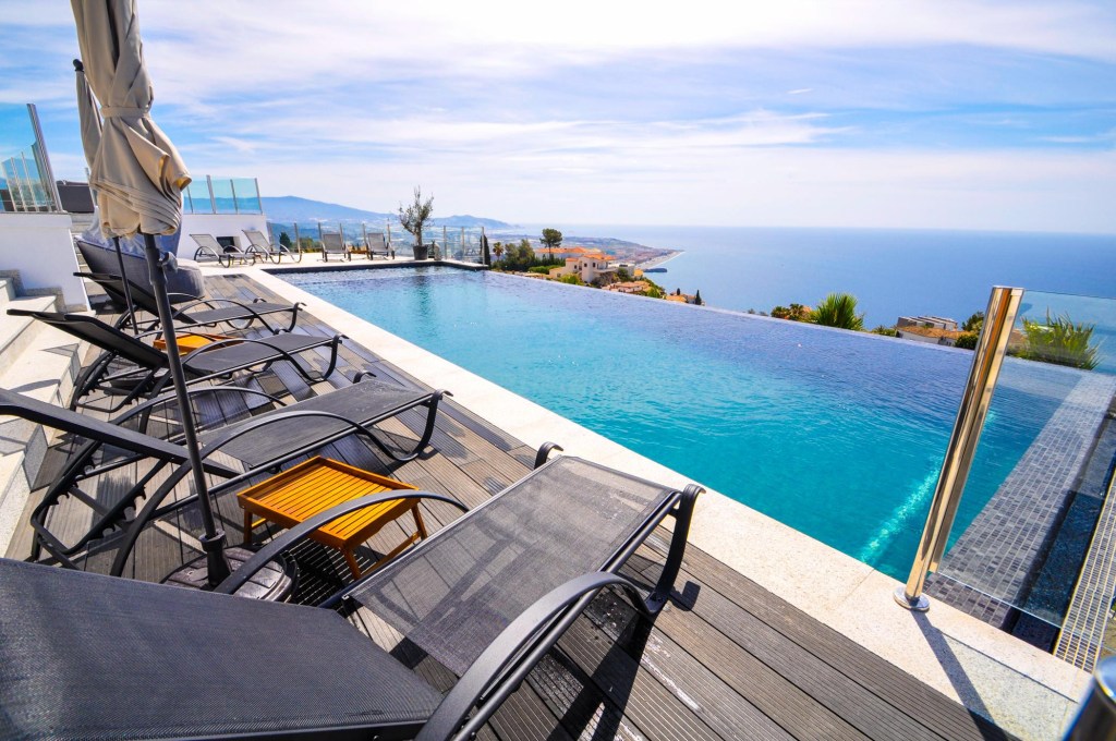 Infinity pool overlooking the ocean with lounge chairs beside it.