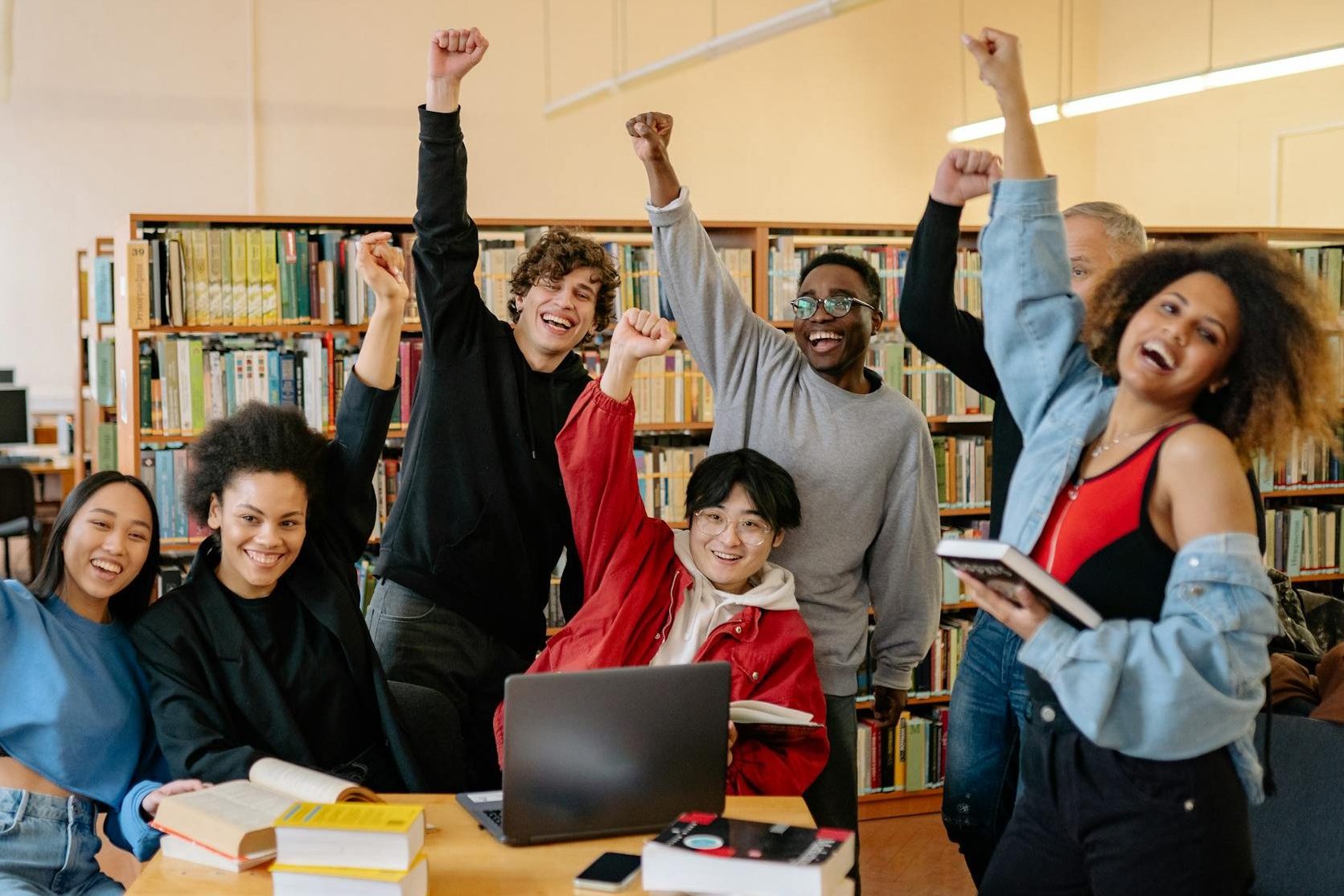 group of people smiling and standing near brown wooden table raising handsPhoto by Yan Krukau on Pexels.com
